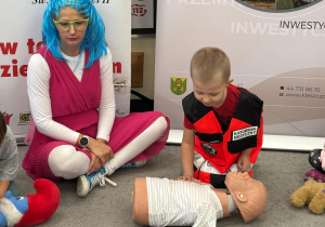 Chłopiec przebrany w strój ratownika udziela pierwszej pomocy.