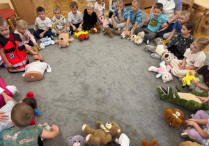 Dzieci ze swoimi maskotkami siedzą w kole.