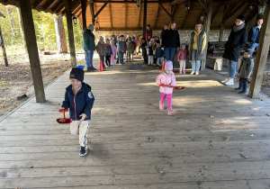 Przedszkolaki biegną z ziemniakami na łopatach.