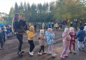 Dzieci razem z nauczycielami tańczą w kole.