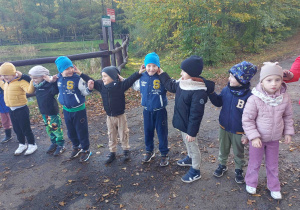 Pięciolatki śpiewają piosenkę i trzymają się za uszy.