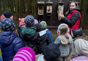 Pani pokazuje dzieciom budki ptaków.