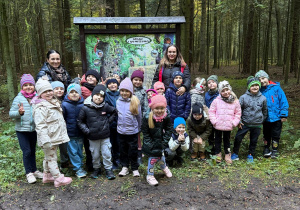 Dzieci pozują do wspólnego zdjęcia w lesie.