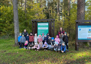 Dzieci stoją przy znaku rezerwatu w lesie.