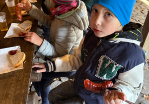 Chłopiec trzyma kiełbaskę.