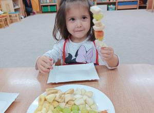 Dziewczynka pokazuje swój owocowy szaszłyk