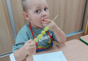 Chłopiec zjada owocowego szaszłyka