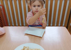 Dziewczynka nabija owoce na drewniany patyk