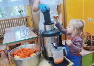 Dziewczynka wrzuca warzywa do sokowirówki