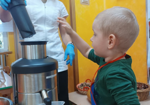 Chłopiec wrzuca jabłko do sokowirówki