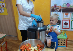 Chłopiec wrzuca jabłko do sokowirówki