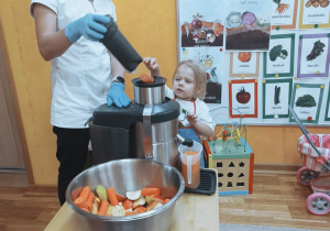 Dziewczynka wrzuca jabłko do sokowirówki