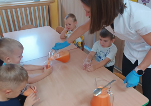 Pani nalewa sok do kubeczków dzieci
