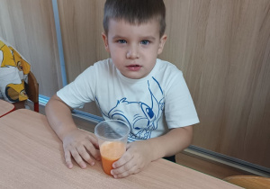 Chłopiec trzyma kubek z sokiem