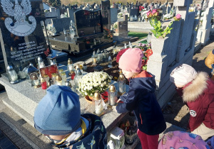 Dziewczynka stawia znicz na grobie poległych w walce o naszą ojczyznę.