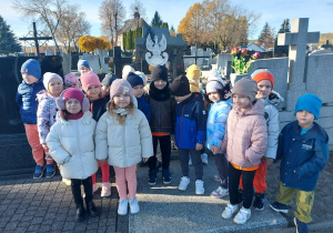 Dzieci stoją przed grobem poległych w walce o naszą ojczyznę.