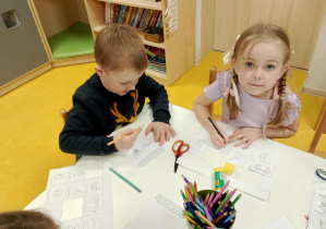 Dzieci uzupełniają książeczki przy stoliczku.