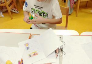 Chłopiec uzupełnia książeczkę o kolejną postać.