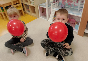 Dzieci dmuchają czerwone balony.