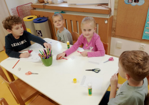 Dzieci wykonują zadanie przy stoliczku.