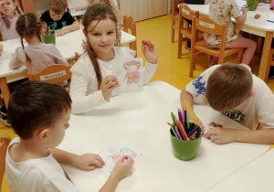 Dzieci kolorują Gniewka przy stoliczku.