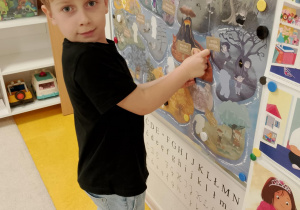 Chłopiec przyczepia sylwetę Gniewka na wyspie złości.