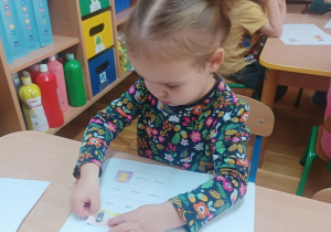 Dziewczynka przykleja postać Markotka do książeczki