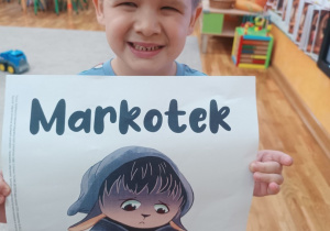 Chłopiec pokazuje ilustracje z postacią Markotka