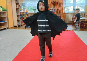 05.Chłopiec w stroju Nietoperza idzie po czerwonym dywanie
