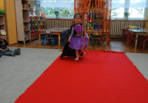 08. Dziewczynka idzie po czerwonym dywanie.