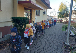 Dzieci ustawionejedno za drugim wyruszają z kijkami z przedszkola