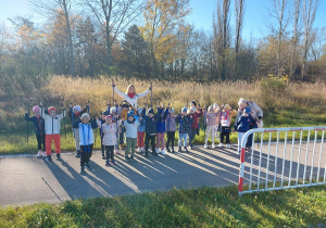 Dumne przedszkolaki pozują do zdjęcia z uniesionymi w górę kijkami