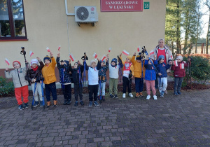 Chłopcy z panią i uniesionymi do góry kijkami pozują do zdjęcia