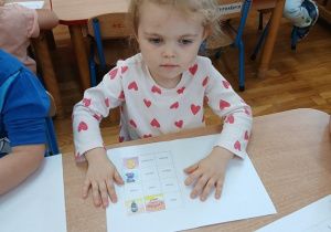 11. Dziewczynka wkleja obrazek do książeczki.