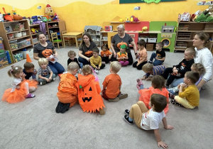 Dzieci siedzą na dywanie.