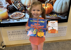 Dziewczynka trzyma nagrodę i dyplom.