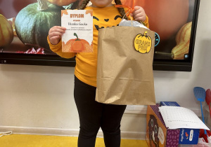 Dziewczynka trzyma nagrodę i dyplom.