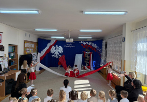 Dziewczynki tańczą z materiałami w barwach Polski.