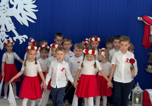 Dzieci idą w czwórkach w tańcu.