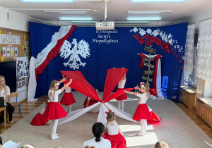 Dziewczynki tańczą z biało czerwonymi materiałami.