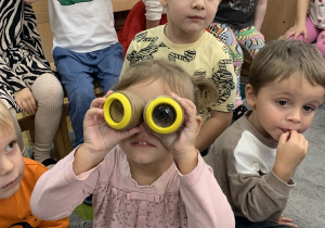 Dziewczynka przykłada lupy do oczu.