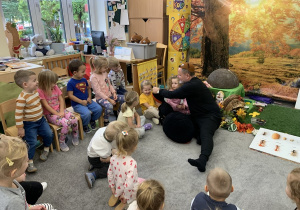 Pan Prowadzący zajęcia pokazuje dzieciom dużą maskotkę mrówki.