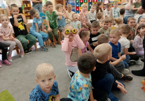 Dziewczynka patrzy przez żółte lupy, które wyglądają jak okulary.