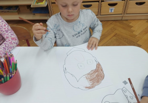 Chłopiec maluje siebie jak wygląda gdy jest smutny.