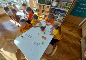 Dzieci wklejają Gniewka do swoich klaserów.