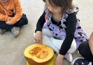 Dziewczynka ogląda co znajduje się w środku dyni.
