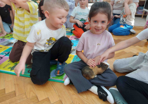 Dziewczynka głaszcze świnkę.