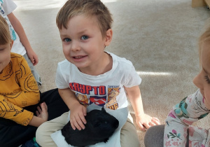 Chłopiec głaszcze czarną świnkę morską.