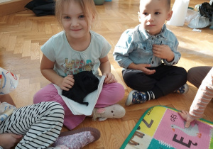 Dziewczynka trzyma świnkę na swoich kolanach.