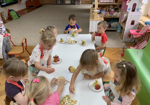 Dzieci wykonują owocowego jeża z jabłek, bananów, winogronu.